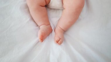 Bebek bacakları. Bebek yatakta uzanıyor ve bacaklarını seğiriyor. Küçük ayaklar. Yeni doğmuş. Yüksek kalite 4k görüntü