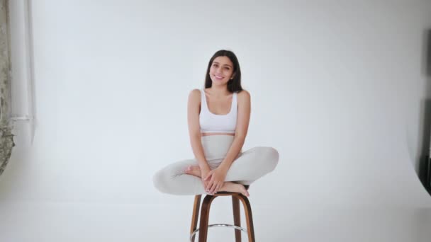 Young Brunette Girl Poses Camera Studio White Background Sitting Chair — Stok video