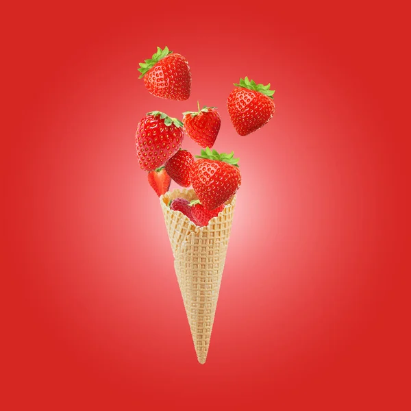 Waffle cornet with strawberries on a red background. Creative fruit concept. Splashing strawberry ice cream. ice cream hanging in the air. Strawberries fly out of a waffle cone.