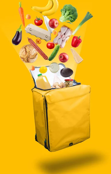 Vegetables, products that flying out of a open yellow courier food delivery bag, isolated on a yellow background. Fresh food delivery concept.