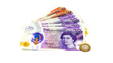 İngiliz 20 ve 10 sterlinlik banknotlar yığını. Beyaz arka planda 1 sterlin madeni para var.