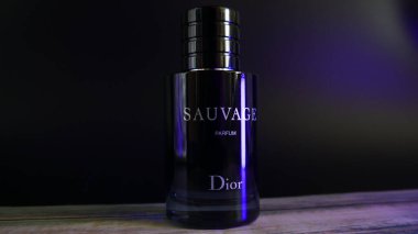 Dior Sauvage Parfüm Şişe Kırsal boyalı masa üzerinde mavi aksanlı ışıklandırma