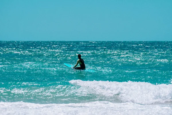 surfer sitting on the surfboard in the water