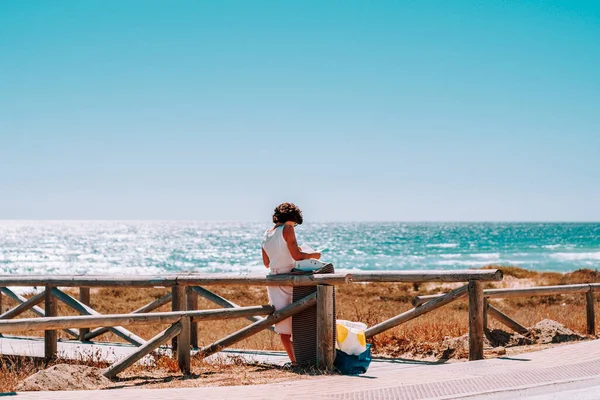 woman reading on the pier near the beach