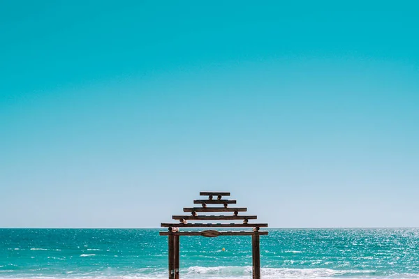 view of the pier on a blue beach with a big blue sky
