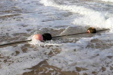 A rope with floats on the city beach enclosing safe swimming areas. 