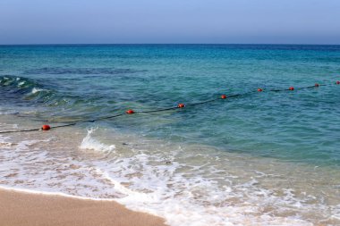 A rope with floats on the city beach enclosing safe swimming areas. 