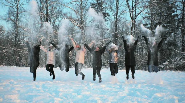 Cheerful girls throw snow on the background of a snow-covered forest.