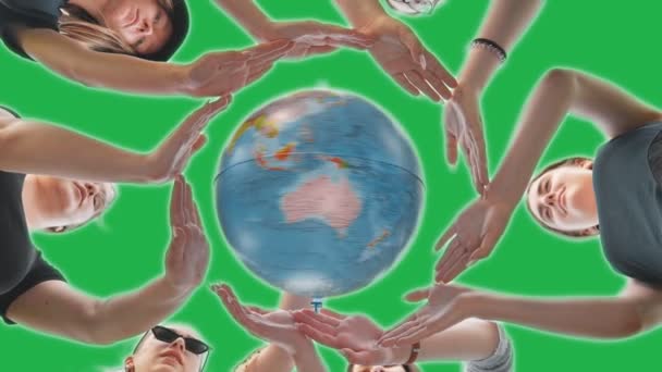 Schoolgirls girls hug the earth globe with their hands, making a circle out of them on a green background.