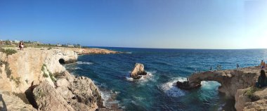 Güzel manzaralı kayalık bir sahil ve arka planda açık mavi bir gökyüzü..