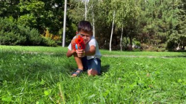 A boy playing with his nerf gun at the park. 