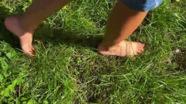 A young boy walking on the grass, feet walking, little foot, barefoot on the grass