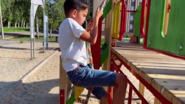 A boy plays on the playground, swing, outdoor games.