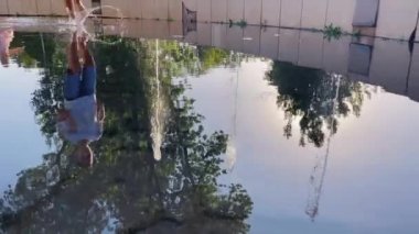 Young boy near the fountain, water drops, slowmotion, running. Foot runs at the water. Child.