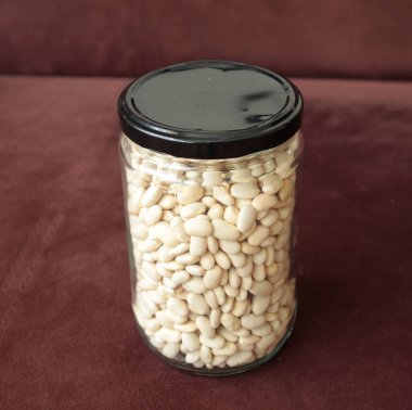 Beyaz arka planda fasulye dolu cam kavanoz.
