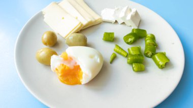 Haşlanmış yumurta, taze çedar peyniri, yeşil zeytin, biber ve süzme peynirden oluşan besleyici ve besleyici bir kahvaltı..