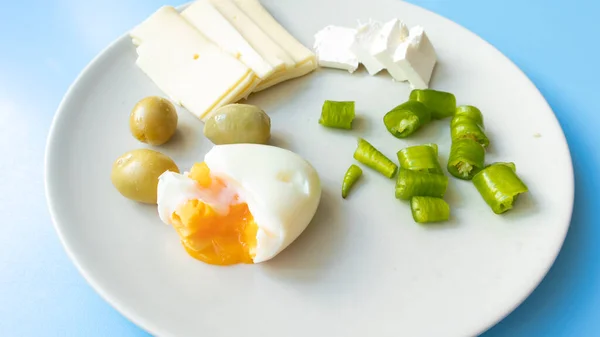 Haşlanmış yumurta, taze çedar peyniri, yeşil zeytin, biber ve süzme peynirden oluşan besleyici ve besleyici bir kahvaltı..