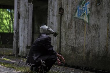 Siyah takım elbiseli, gaz maskesi takmış güzel bir Ukraynalı kız beton zeminde yatıyor ve terk edilmiş bir fabrikanın etrafında dolaşıyor..
