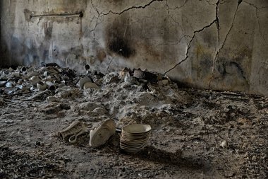 A flat in the town of Borodyanka after being hit by a shell. A burned electric cooker, cracked wall and ashes from furniture, burnt flowers and children's shoes.