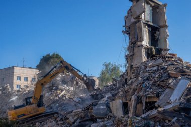Gostomel, Kyiv Ukrayna - 25 Eylül. 2022: Bir kazıcı kovayla bir evi yok etti. Ev, Rus birlikleri tarafından işgal sırasında hasar gördü ve bir bomba tarafından vuruldu.. .