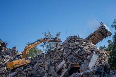Gostomel, Kyiv Ukrayna - 25 Eylül. 2022: Bir kazıcı kovayla bir evi yok etti. Ev, Rus birlikleri tarafından işgal sırasında hasar gördü ve bir bomba tarafından vuruldu.. .