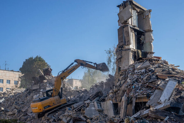 Гостомель, Киев Украина - 25 сентября. 2022: Экскаватор разрушает дом с ведром. Дом был поврежден во время оккупации русскими войсками и был сбит бомбой.. .