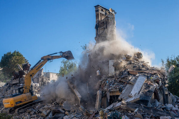 Гостомель, Киев Украина - 25 сентября. 2022: Экскаватор разрушает дом с ведром. Дом был поврежден во время оккупации русскими войсками и был сбит бомбой.. .