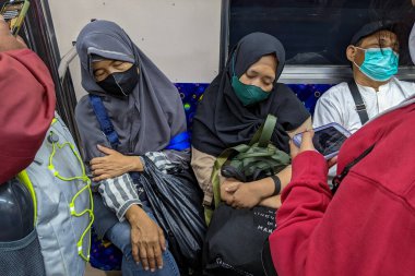 İşten eve giden iki kadın ya banliyö hattında ya da tren yolcuları arasında uyuyorlar. Jakarta, Endonezya - 27 Mayıs 2022