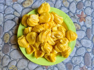 Fresh yellow jackfruit on a green plate.