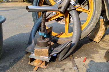 Sızdıran bir motosiklet lastiğini onarma işlemi (Tambal Ban). Sızdıran bir motosiklet lastiğini onarmak için kullanılan bir araç.