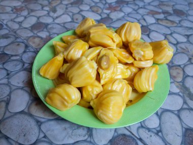 Fresh yellow jackfruit on a green plate.