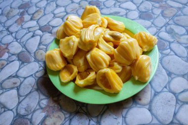 Fresh yellow jackfruit on a green plate.