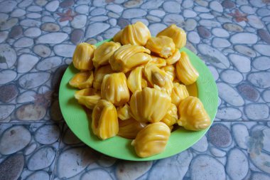 Fresh yellow jackfruit on a green plate.