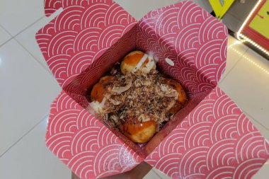 Selective focus of delicious Takoyaki in a red wrap.