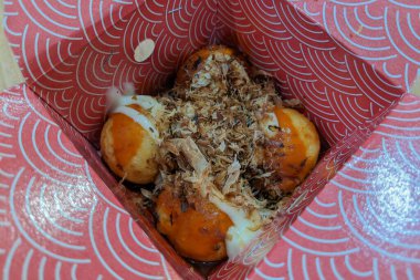 Selective focus of delicious Takoyaki in a red wrap.