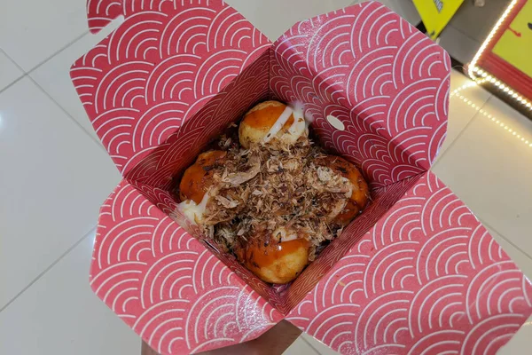 Selective focus of delicious Takoyaki in a red wrap.