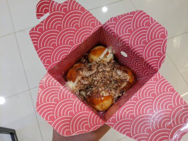 Selective focus of delicious Takoyaki in a red wrap.