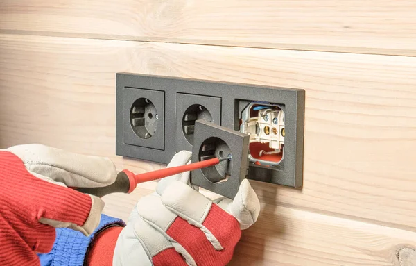 installation of a block of three black sockets on a wooden wall.