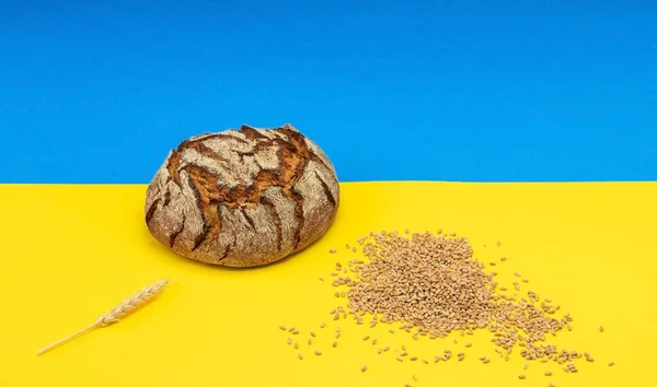 Ukrainian bread and grains of wheat on the background of the flag of Ukraine.