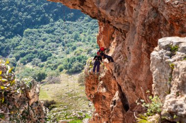 Shlomi, İsrail, 19 Aralık 2020: İki sporcu, dağdan Kuzey İsrail 'deki Keshet Mağarası' na halatla iniyor - tırmanıyor - ip kopuyor -.