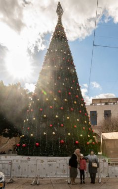 Bethlehem, Israel, December 25, 2021 : A Christmas tree decorated in celebration of Christmas on the crowded central Manager Square Street in Bethlehem in the Palestinian Authority, Israel