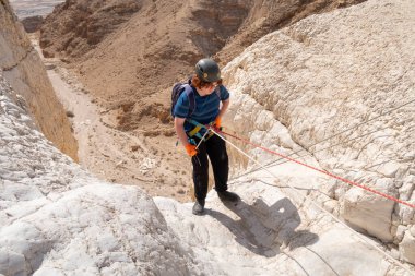 Kudüs, İsrail, 16 Nisan 2022: Genç bir atlet, İsrail 'in Kudüs yakınlarındaki Tamarim deresi yakınlarındaki Judean Çölü' nün dağlarında kırma teçhizatı kullanarak yokuş aşağı inmeye başladı