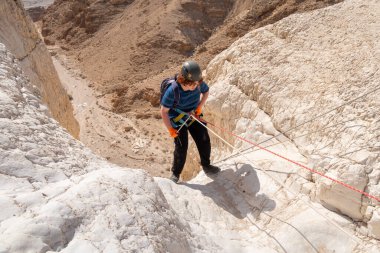 Kudüs, İsrail, 16 Nisan 2022: Genç bir atlet, İsrail 'in Kudüs yakınlarındaki Tamarim deresi yakınlarındaki Judean Çölü' nün dağlarında kırma teçhizatı kullanarak yokuş aşağı inmeye başladı
