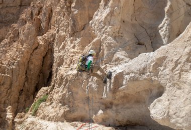 Kudüs, İsrail, 16 Nisan 2022: Deneyimli bir atlet, İsrail 'in Kudüs yakınlarındaki Tamarim deresi yakınlarındaki Musevi Çölü' nün dağlarında kırılma ekipmanlarıyla birlikte iniyor.