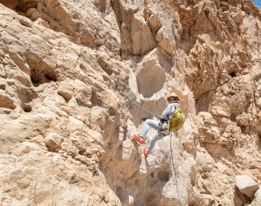Kudüs, İsrail, 16 Nisan 2022: Deneyimli bir atlet, İsrail 'in Kudüs yakınlarındaki Tamarim deresi yakınlarındaki Musevi Çölü' nün dağlarında kırılma ekipmanlarıyla birlikte iniyor.