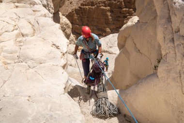 Kudüs, İsrail, 16 Nisan 2022: Deneyimli bir atlet, İsrail 'in Kudüs yakınlarındaki Tamarim deresi yakınlarındaki Musevi Çölü' nün dağlarında kırılma ekipmanlarıyla birlikte iniyor.