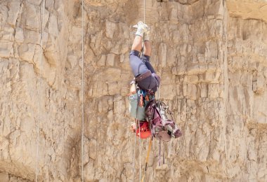 Kudüs, İsrail, 16 Nisan 2022: Tecrübeli bir atlet, İsrail 'in Kudüs yakınlarındaki Tamarim deresi yakınlarındaki Musevi Çölü' nün dağlarında kırılacak aletlerle baş aşağı iniyor.