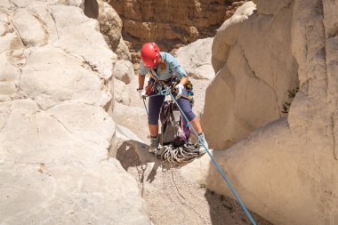 Kudüs, İsrail, 16 Nisan 2022: Deneyimli bir atlet, İsrail 'in Kudüs yakınlarındaki Tamarim deresi yakınlarındaki Musevi Çölü' nün dağlarında kırılma ekipmanlarıyla birlikte iniyor.