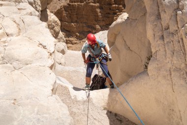 Kudüs, İsrail, 16 Nisan 2022: Deneyimli bir atlet, İsrail 'in Kudüs yakınlarındaki Tamarim deresi yakınlarındaki Musevi Çölü' nün dağlarında kırılma ekipmanlarıyla birlikte iniyor.