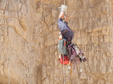 Kudüs, İsrail, 16 Nisan 2022: Tecrübeli bir atlet, İsrail 'in Kudüs yakınlarındaki Tamarim deresi yakınlarındaki Musevi Çölü' nün dağlarında kırılacak aletlerle baş aşağı iniyor.